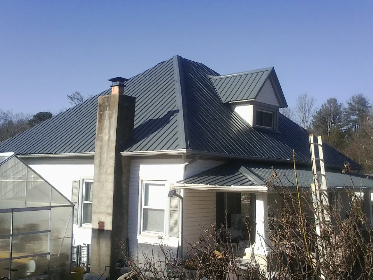 Dark blue standing seam metal roof on a white farmhouse with dormer — Slate & Tile Roof Repair by Roofing Brothers in Hemet