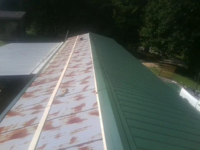 Old rusted panels beside newly installed green metal roofing — Wind Damage Roof Repair by Roofing Brothers in Hemet