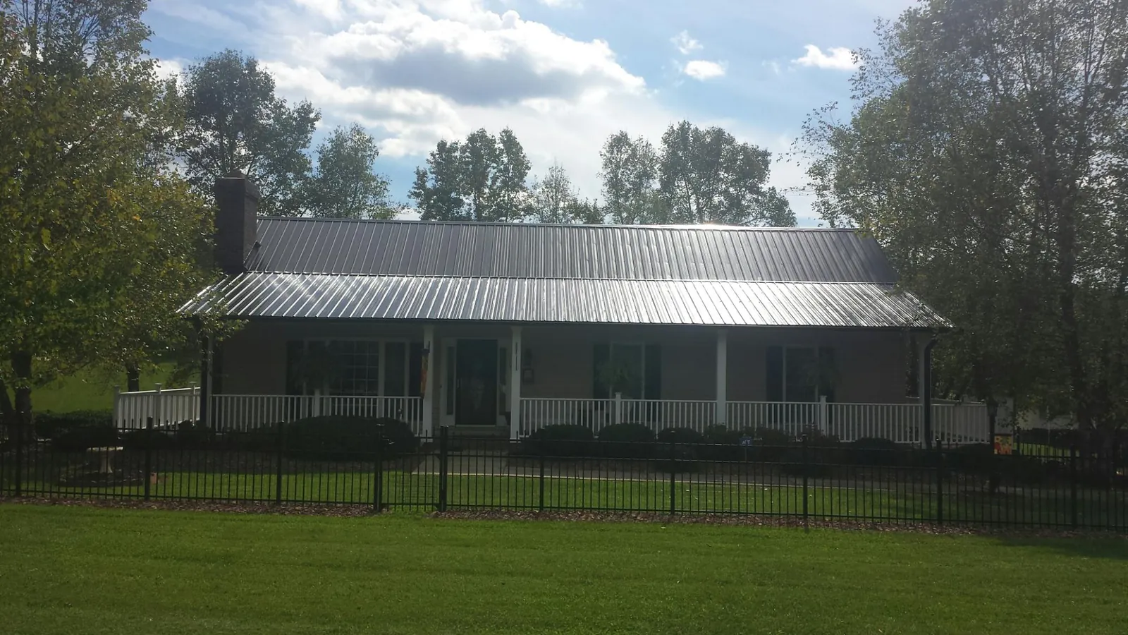 Gray metal roof on a brick ranch with a full width front porch — Gutter Guard Installation work by our crew in Hemet