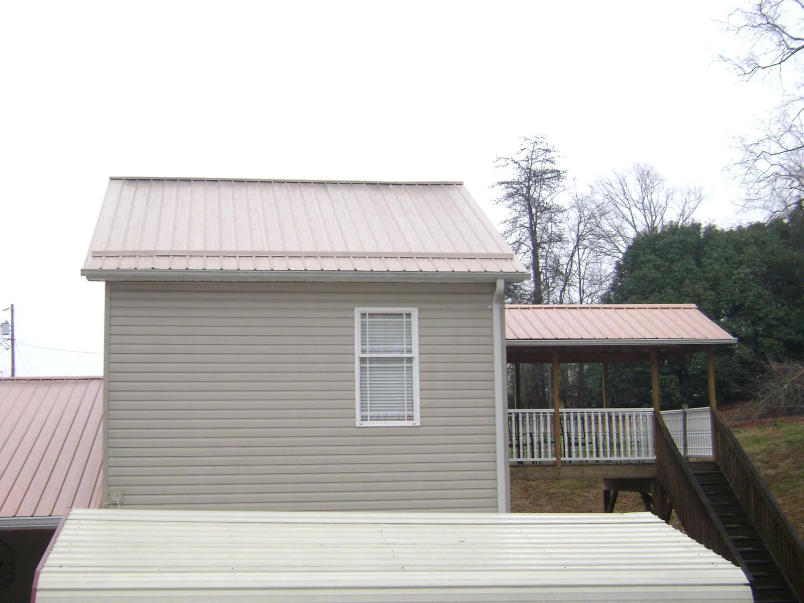 Tan metal roofs on a two story addition and attached porch, from a Roof Replacement job in Hemet